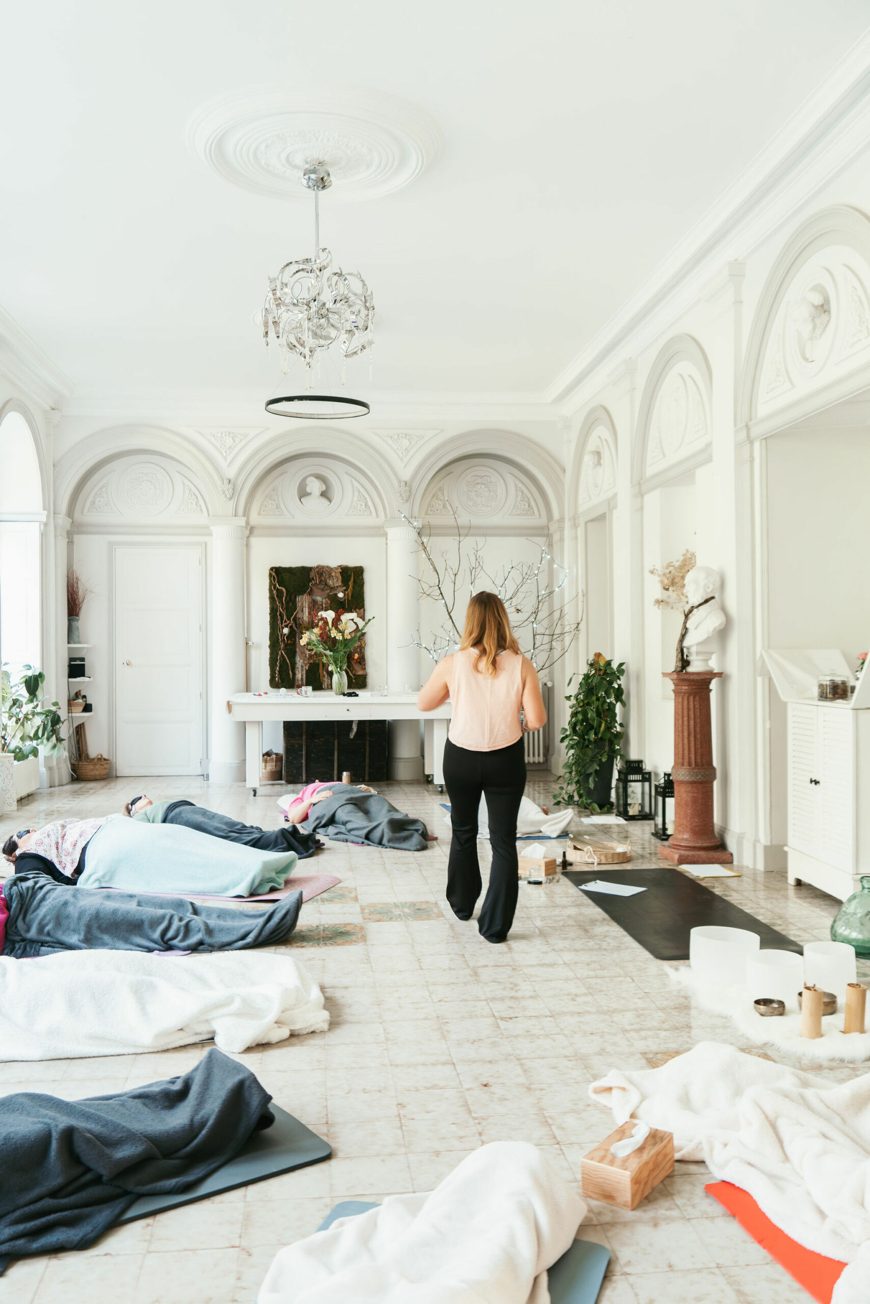Une jeune femme se tient au centre d'une pièce, dans laquelle sont allongées des personnes. Il s'agît d'un cours de respiration